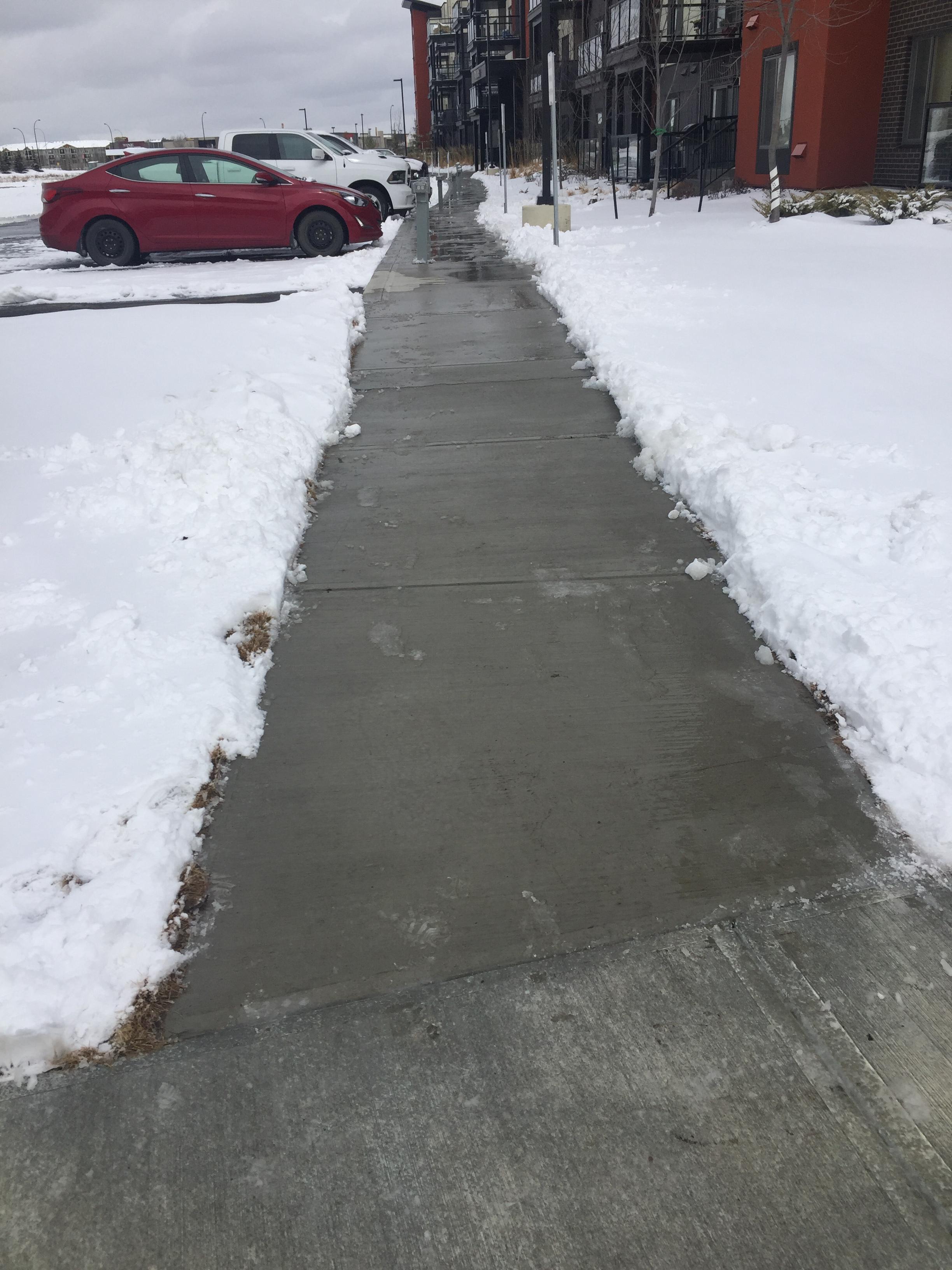 Commercial sidewalk cleared of snow beside apartment buildings